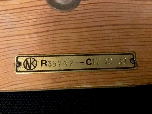 Brass tag with text and logo on a wooden surface