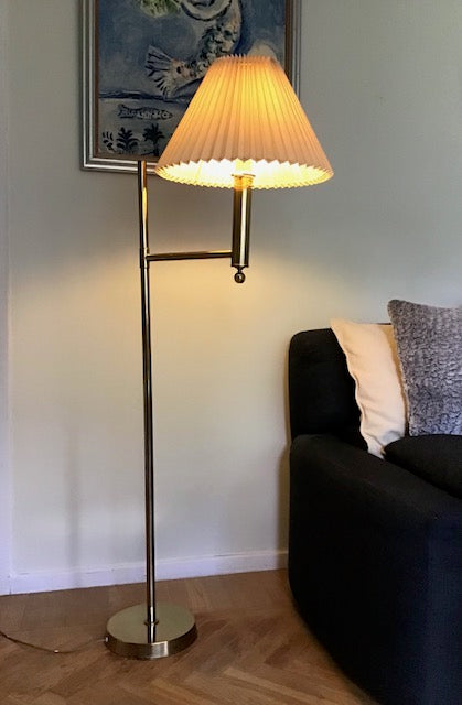 Floor lamp with pleated shade in a room with a sofa and decorative pillows.