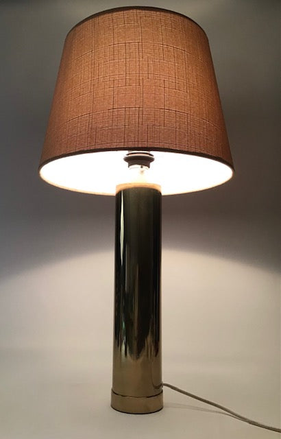 Table lamp with brown fabric shade and black cylindrical base on a neutral background