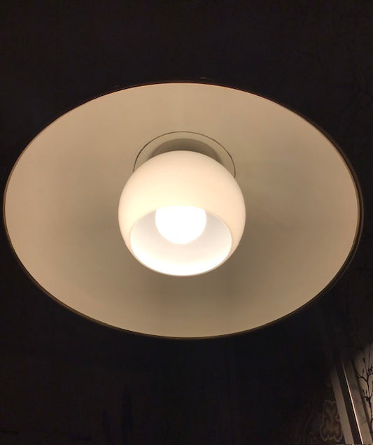 Light bulb inside a white ceiling fixture on a dark background