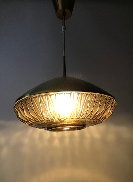 Gold pendant light with textured shade on a dark background