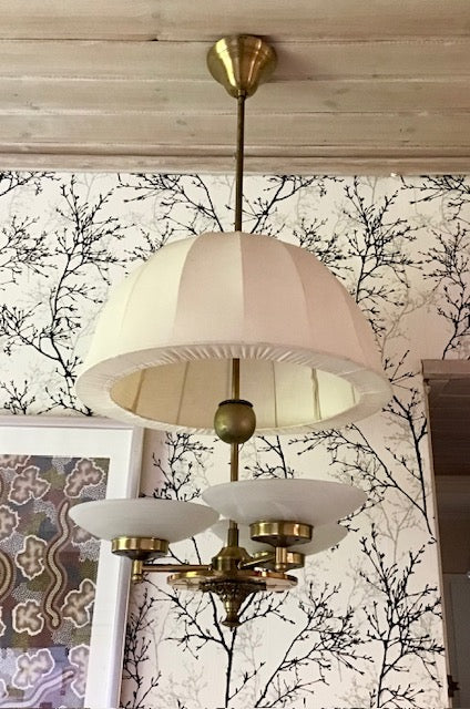 Vintage-style chandelier with striped lampshade against a decorative wall.