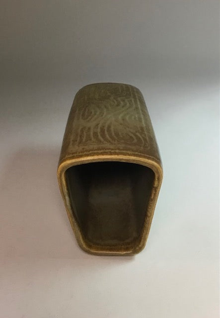 Brown rectangular object with embossed design on a light gray background