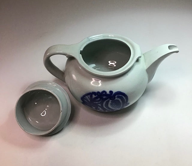 Ceramic teapot with blue floral design on a light gray background