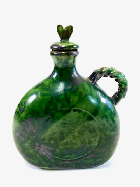 Green ceramic jug with a lid on a white background