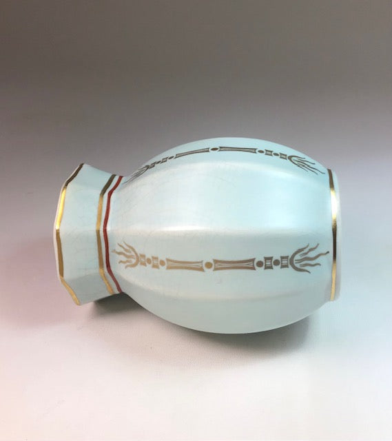Decorative ceramic vase with gold and red patterns on a gradient background