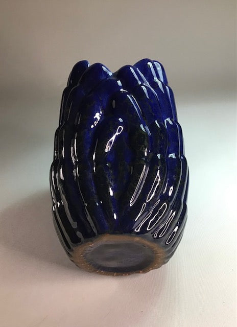 Blue ceramic vase with textured surface on a light gray background
