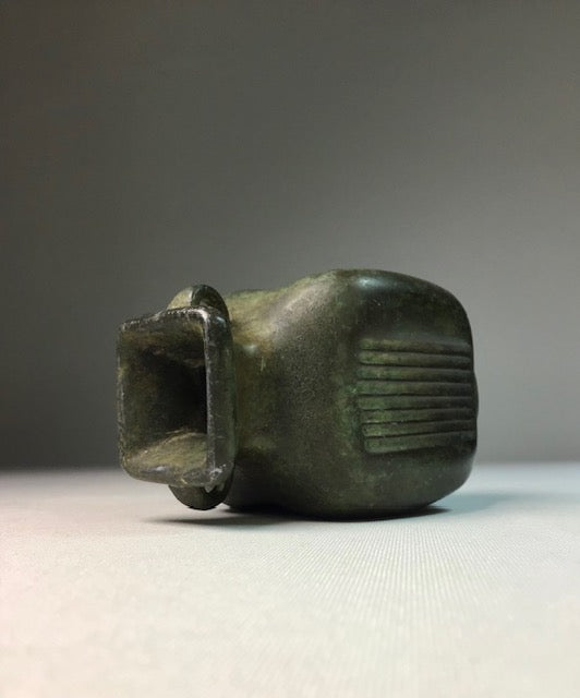 Bronze object with a textured surface on a gray background