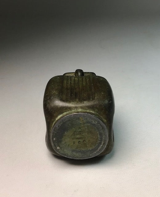 Bronze hourglass-shaped object on a gray background