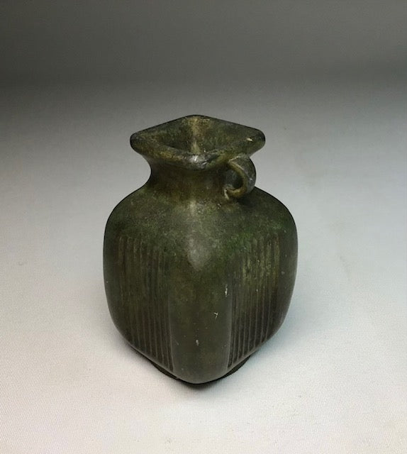 Bronze bottle with ribbed design on a gray background