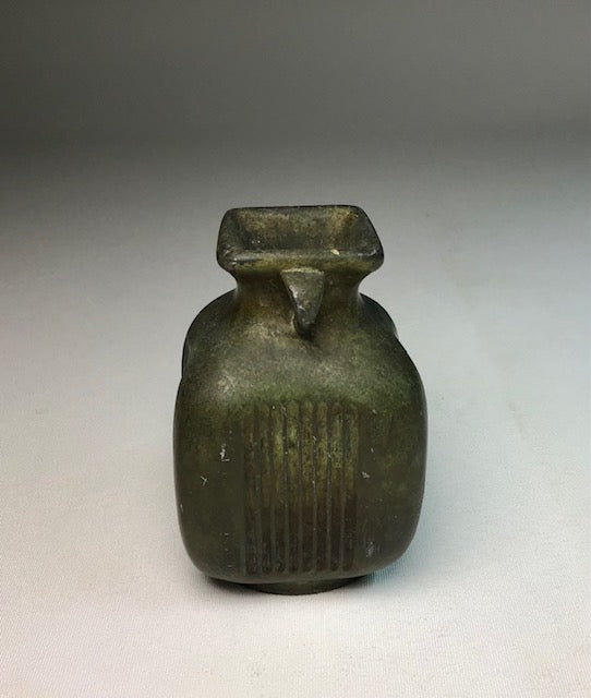 Small green ceramic jar with a square top on a gray background