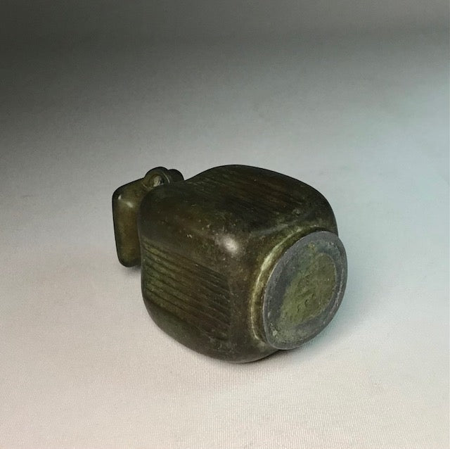 Bronze object with ribbed design on a light gray background