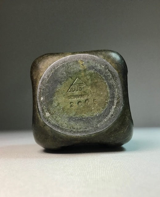 Bronze-colored square object with 'Zeiss' branding on a gray background