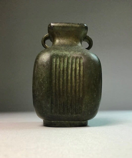 Bronze vase with ribbed design on a gray background