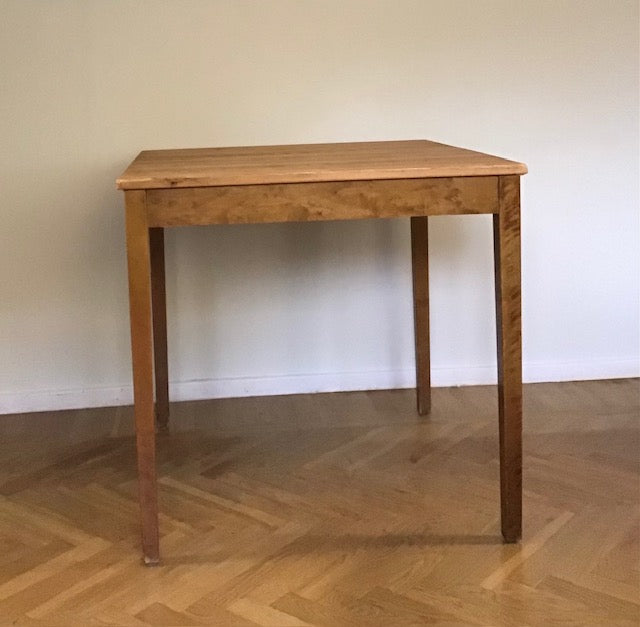 Wooden table on a wooden floor with a plain wall background