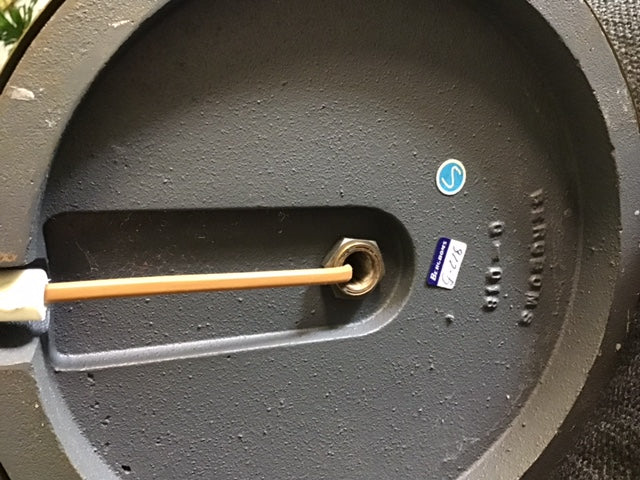 Close-up of a grill with a thermometer probe inserted, showing brand name on the side.
