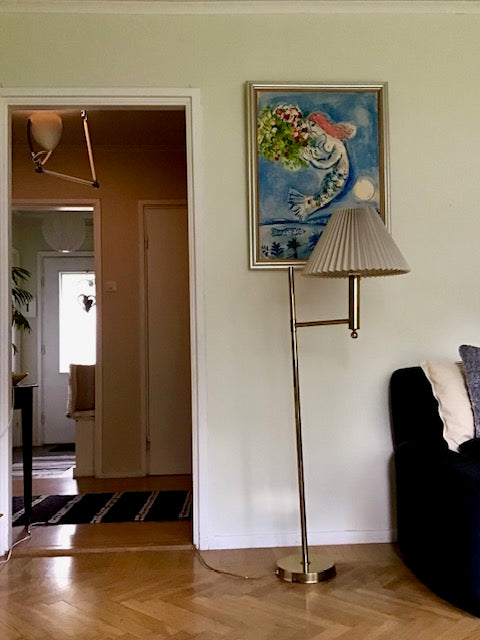 Living room with a lamp, sofa, and painting on the wall.
