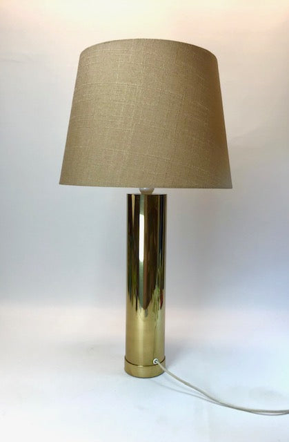 Table lamp with a gold base and beige shade on a white background