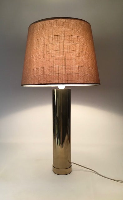 Table lamp with a brown textured shade and metallic base on a neutral background