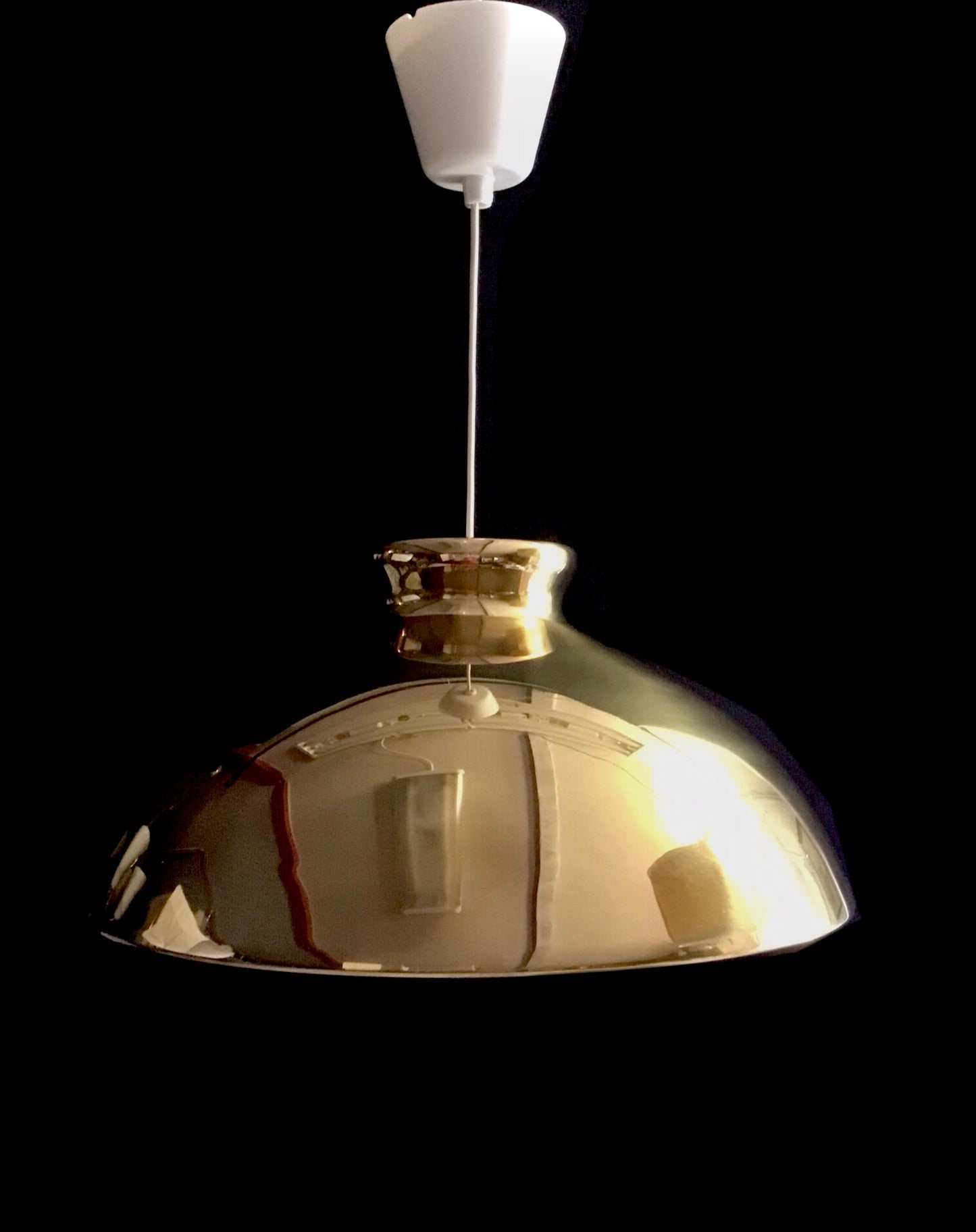 Metallic pendant light with a white bulb on a black background