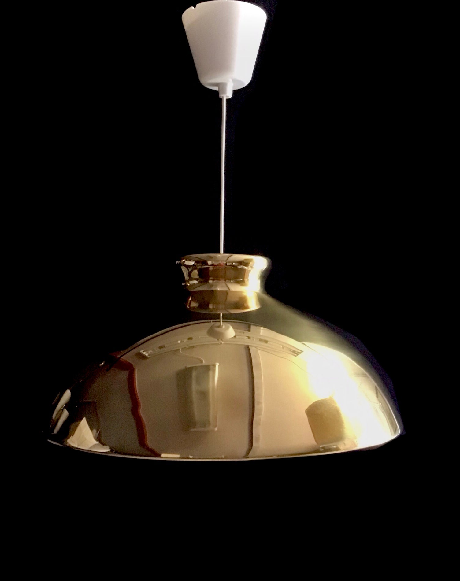 Metallic pendant light with a white bulb on a black background