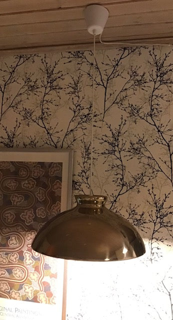 Bronze pendant light fixture hanging against a wall with floral wallpaper