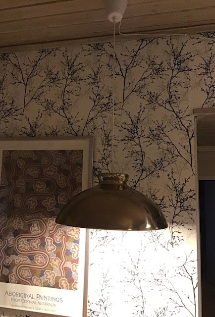Pendant light fixture hanging from a ceiling with a decorative wall in the background