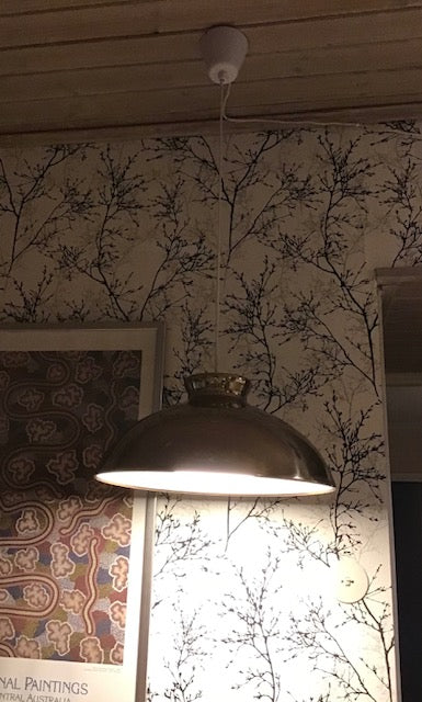 Light fixture hanging from a ceiling with patterned wallpaper in the background