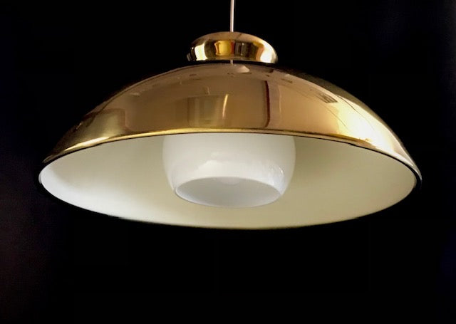 Gold pendant light with white bulb against a black background