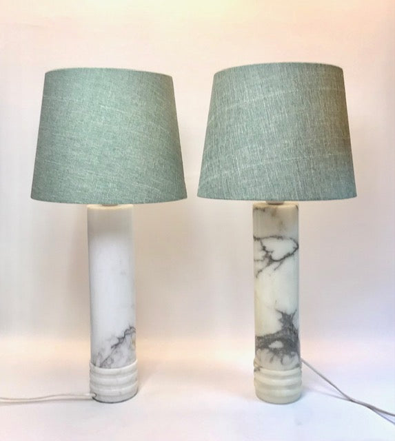 Two table lamps with marble bases and green lampshades on a white background
