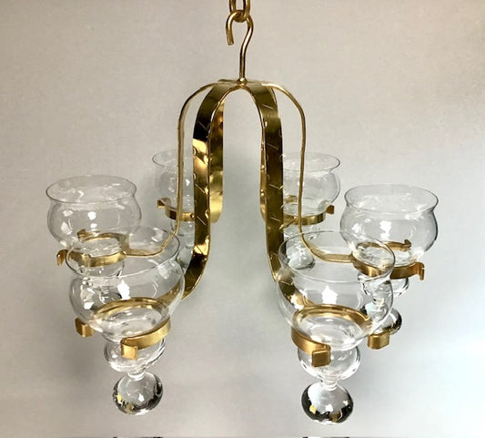 Gold chandelier with clear glass shades on a light gray background