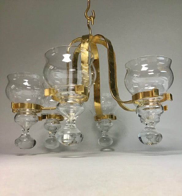Chandelier with gold frame and clear glass shades on a plain background