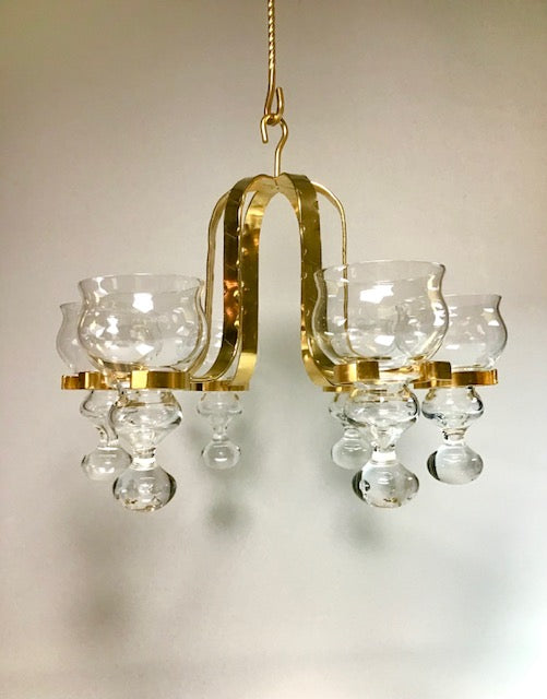 Gold chandelier with clear glass shades on a neutral background