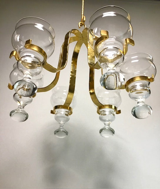 Chandelier with gold frame and clear glass shades on a neutral background