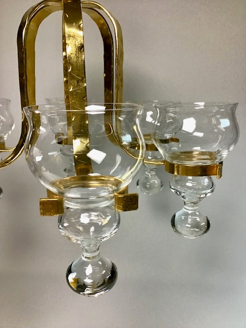 Chandelier with glass shades and gold accents on a neutral background