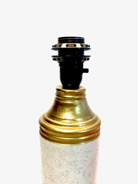 Decorative lamp base with gold and black design on a white background