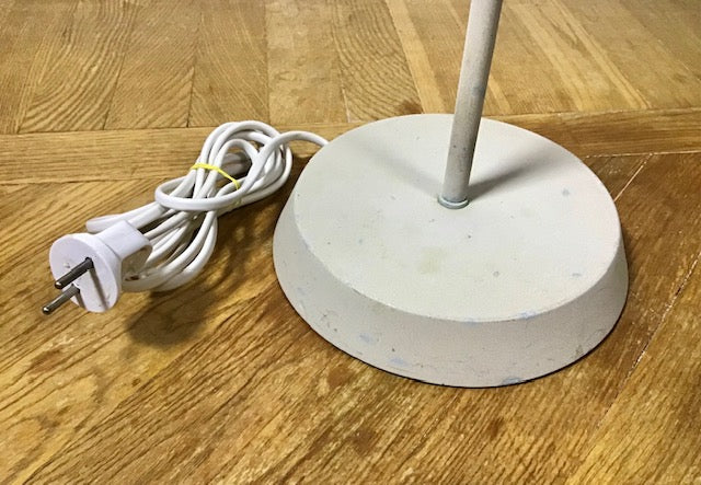 Concrete floor lamp with white cord and plug on a wooden floor