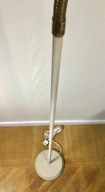 Floor lamp with a white base on a wooden floor against a white wall