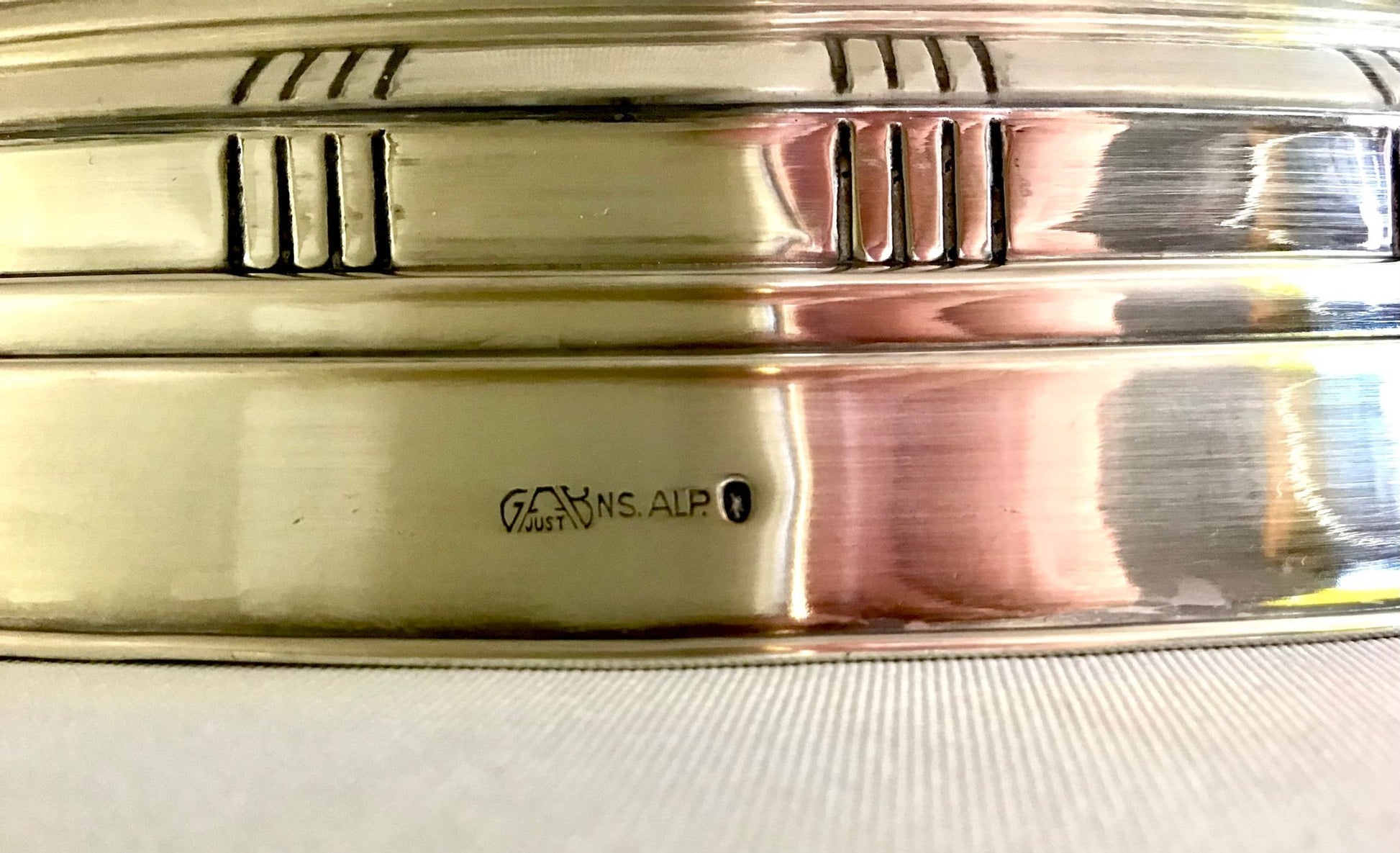 Close-up of a gold object with 'Goldsmiths' hallmark on a white background