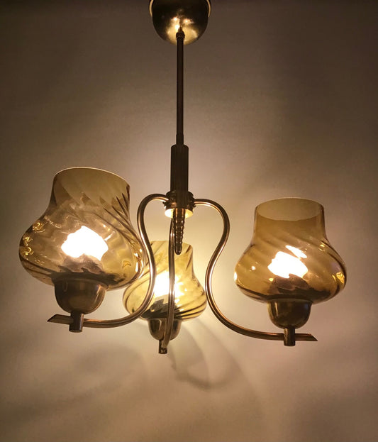 Vintage-style chandelier with three amber glass shades on a plain background