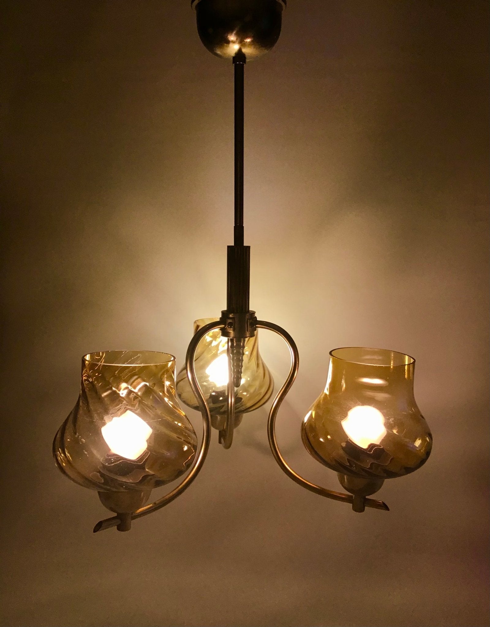 Vintage-style chandelier with three glass shades on a dark background