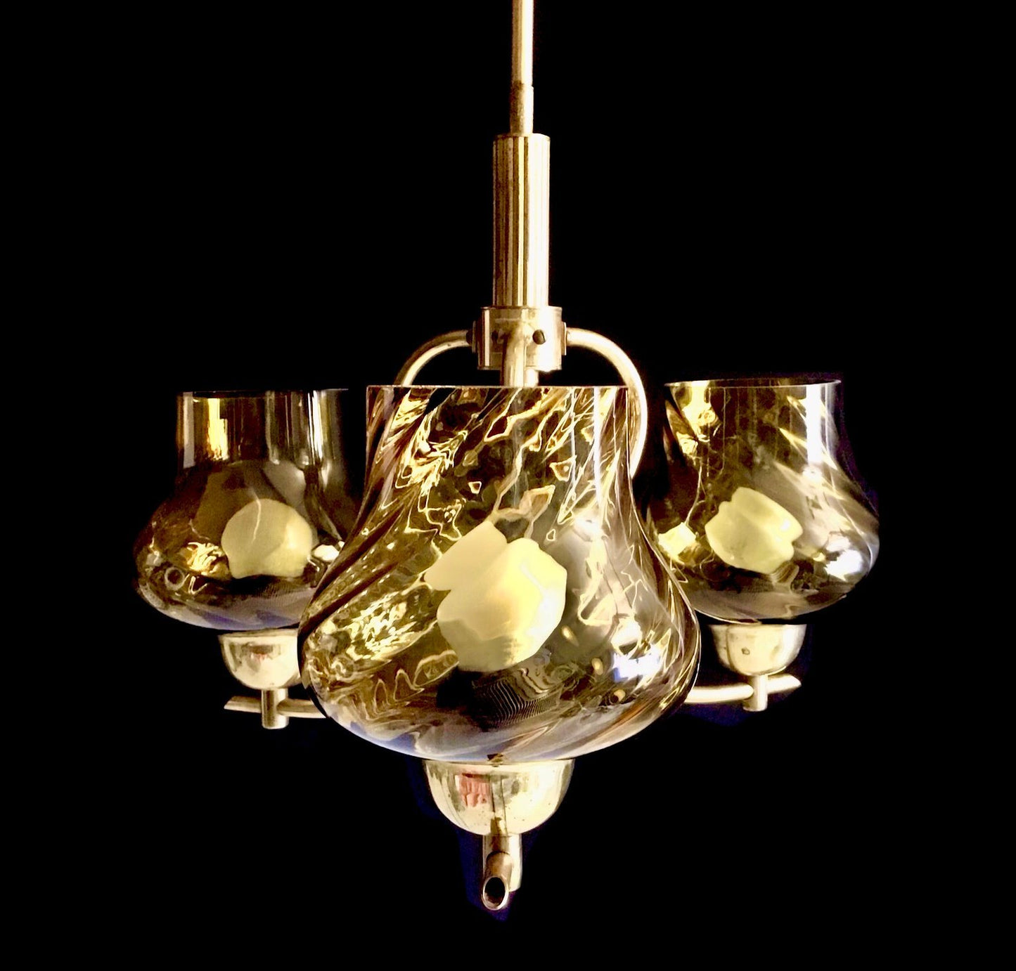 Chandelier with glass shades and brass accents on a black background