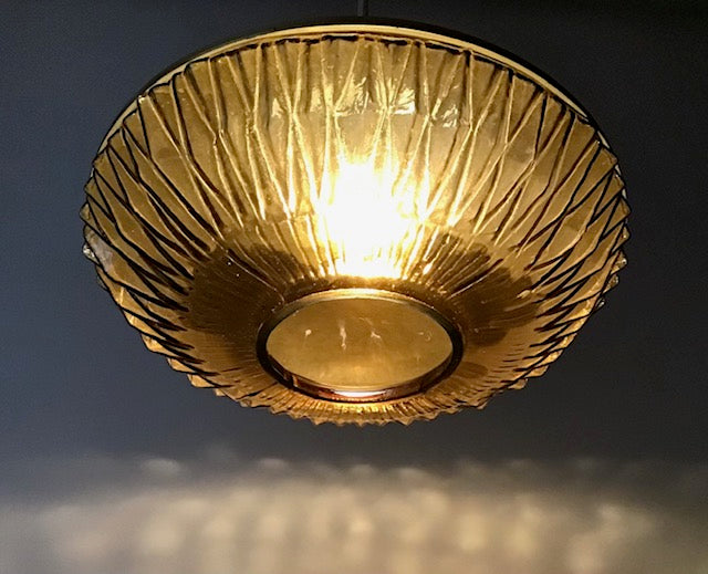 Gold ceiling light fixture with textured design on a dark background