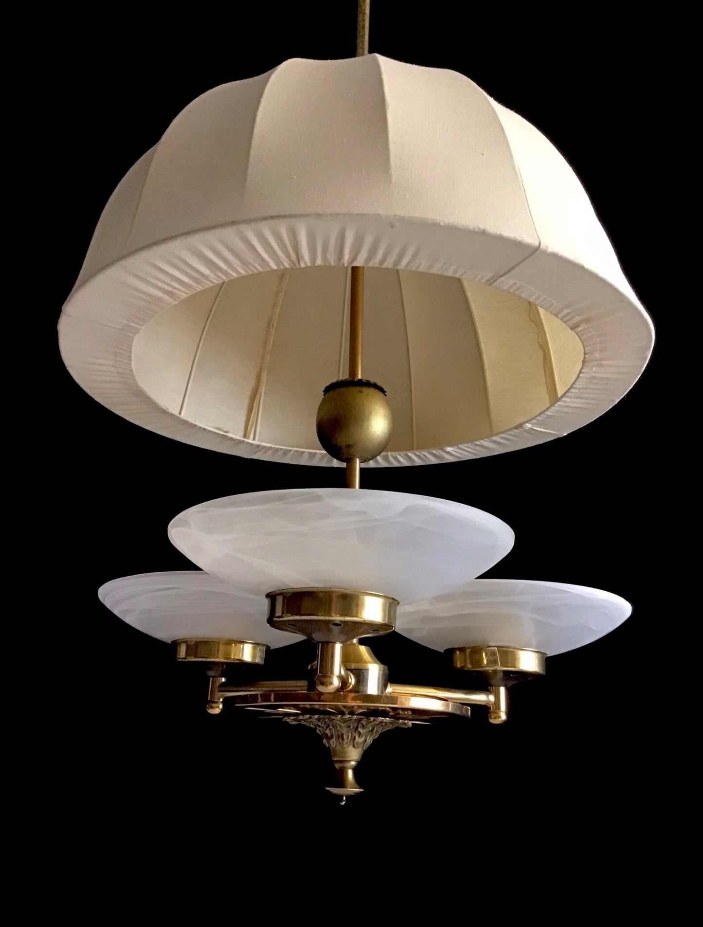 Vintage-style chandelier with white lampshades and gold fixtures on a black background