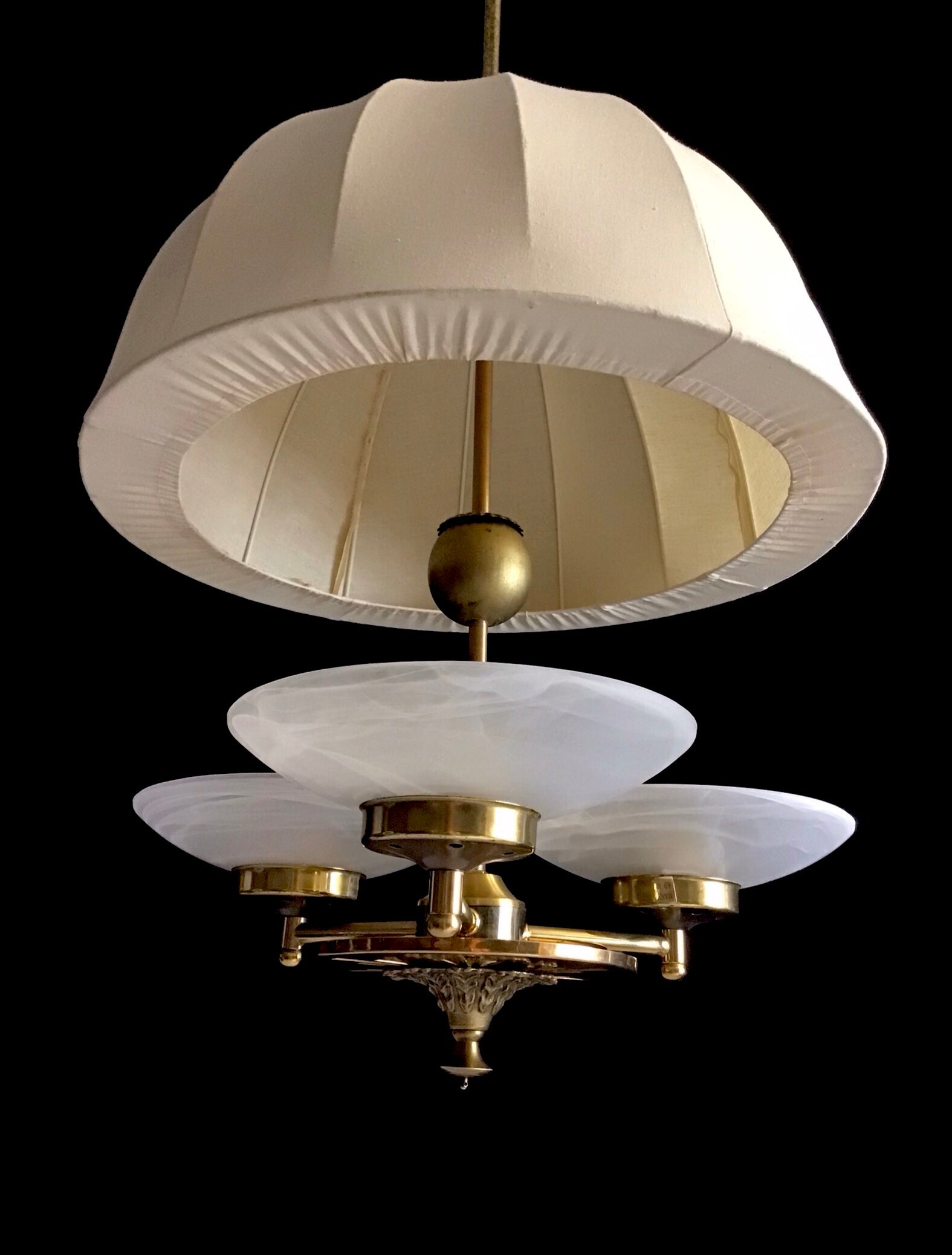 Vintage-style chandelier with white lampshades and gold fixtures on a black background
