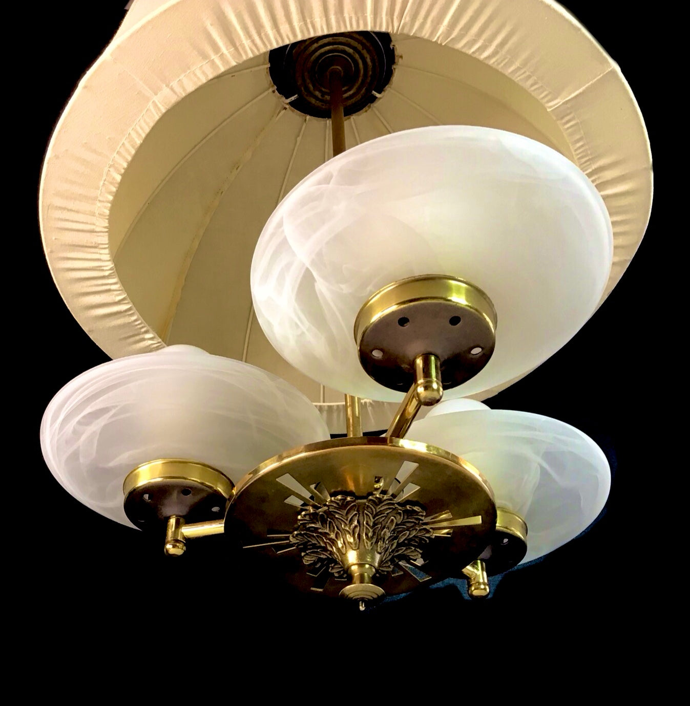 Vintage-style ceiling light fixture with white glass shades and gold metal accents on a black background.