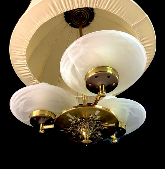Vintage-style ceiling light fixture with white glass shades and gold metal accents on a black background.