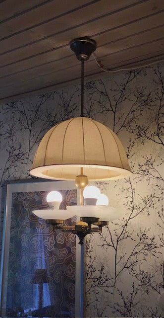 Light fixture hanging from a ceiling with a decorative wall in the background