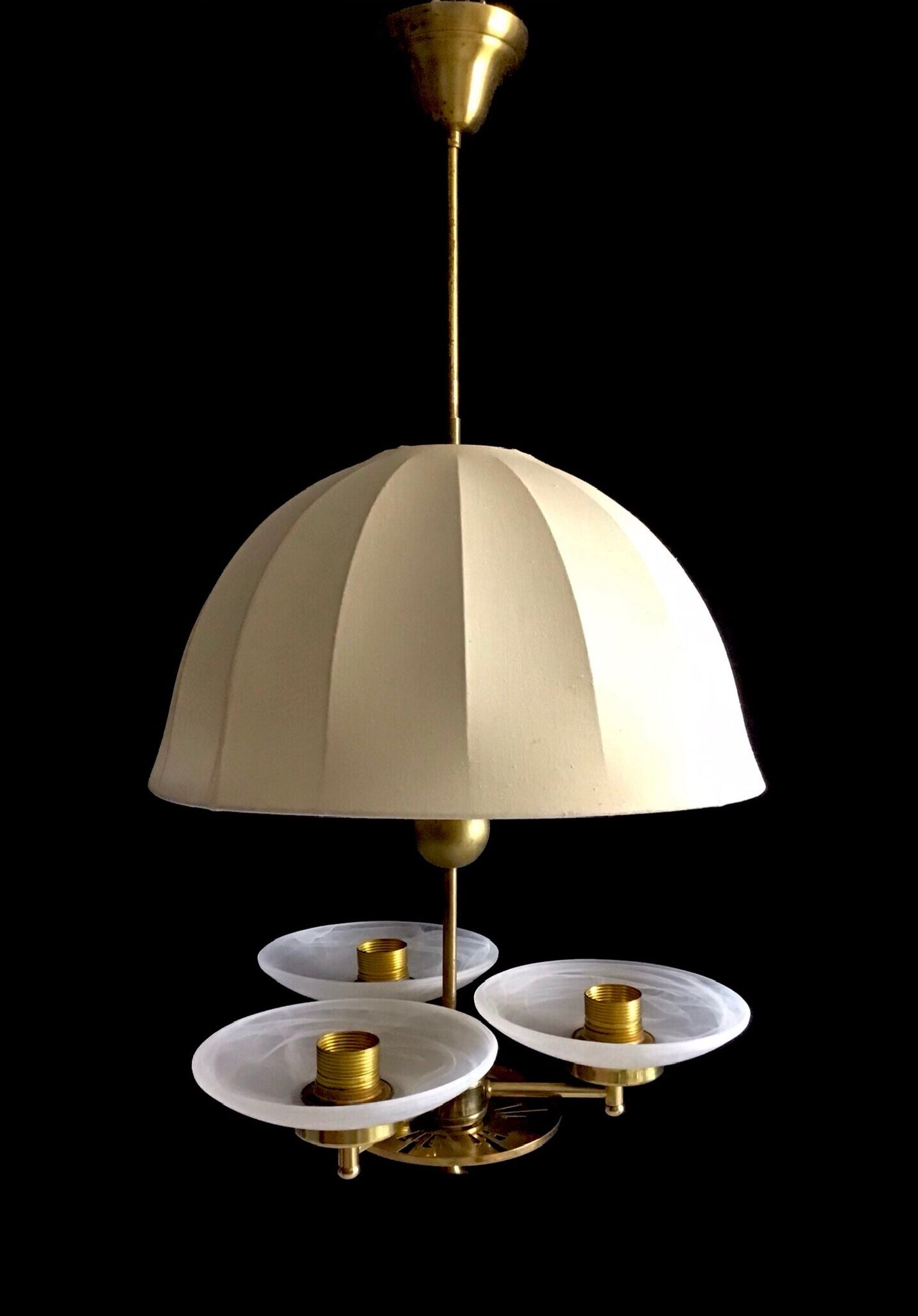 Vintage-style chandelier with beige lampshade and gold accents on a black background