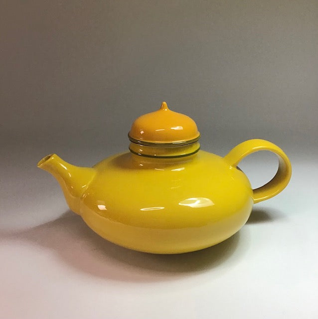 Yellow teapot with a matching lid on a gray background